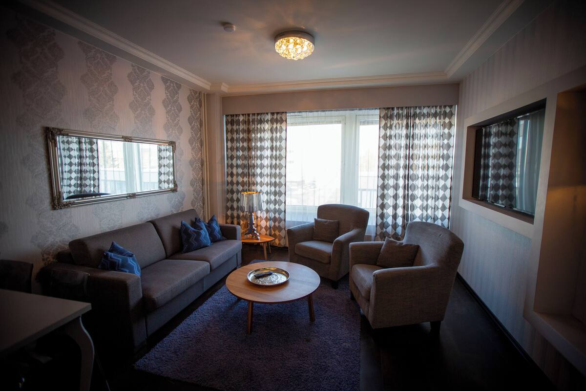 A living room with a sofa, armchairs, a coffee table, and a large mirror.