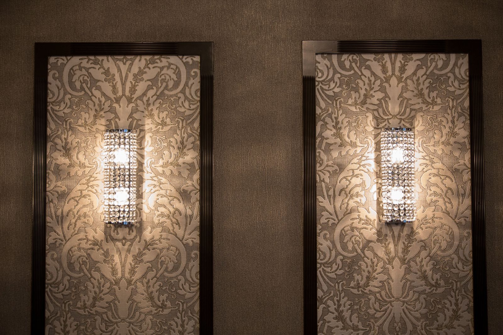 Two wall sconces with intricate patterns and a central light fixture.
