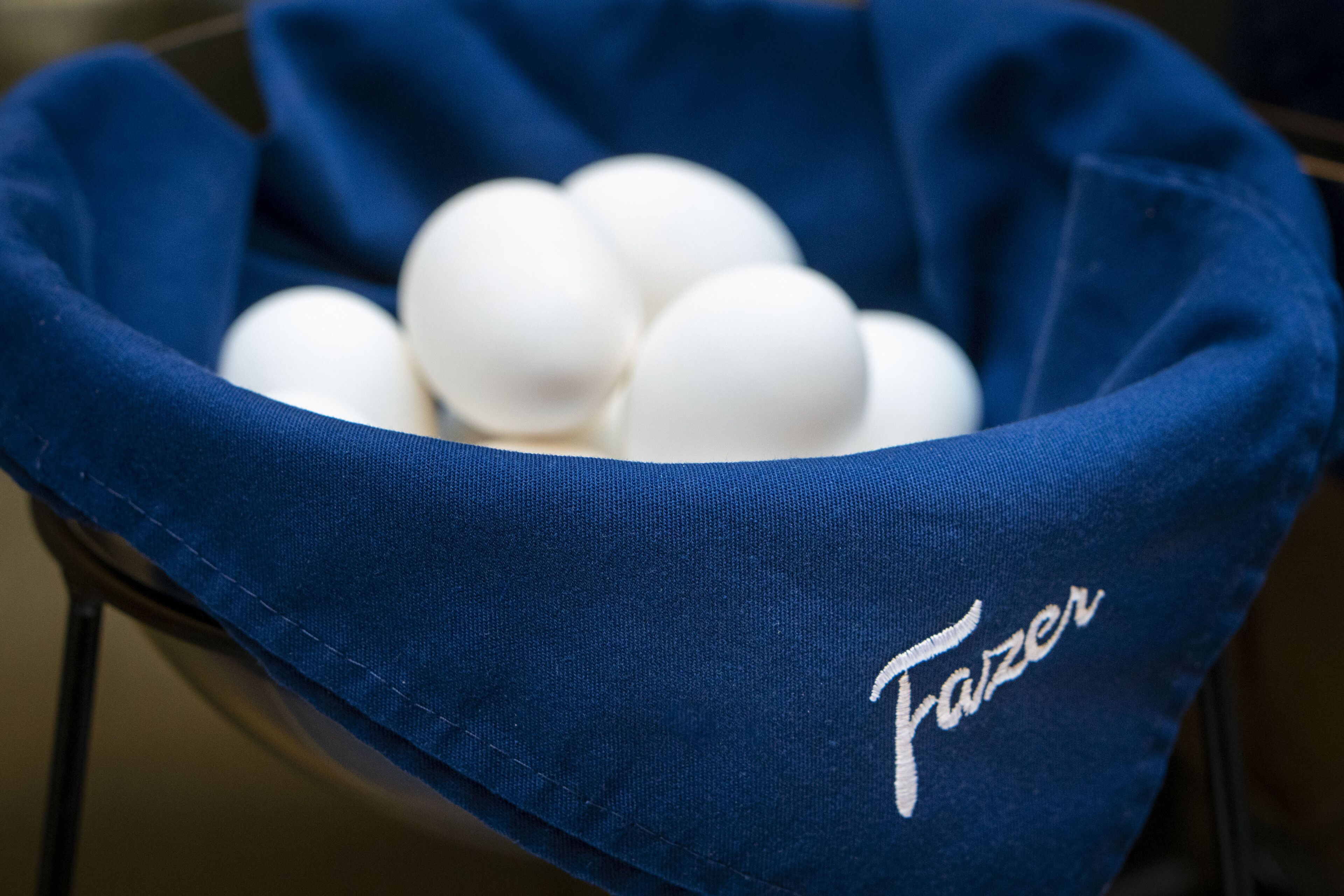 A blue fabric basket containing white eggs.