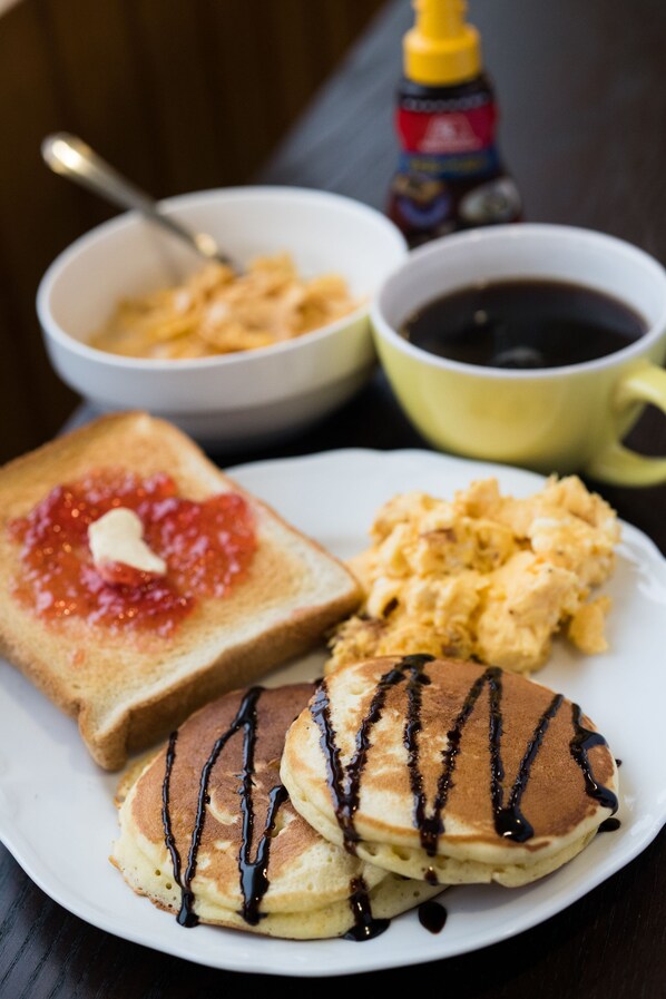 A plate with pancakes, toast with jam, scrambled eggs, and a cup of coffee. - Absolute Niseko (Kutchan)