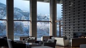 A modern interior with large windows, a fireplace, and a view of a snowy landscape. - River Retreat GARAKU (Toyama)