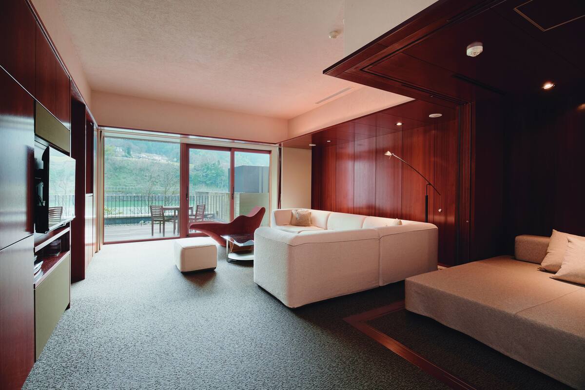 A modern living room with a large white sofa, a red chair, and a flat-screen TV.