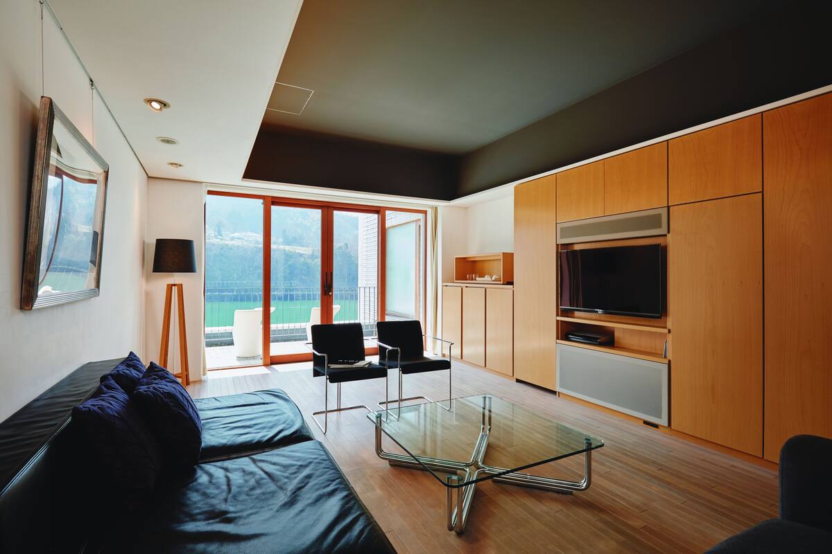 A modern living room with a glass coffee table, a sofa, and a TV.