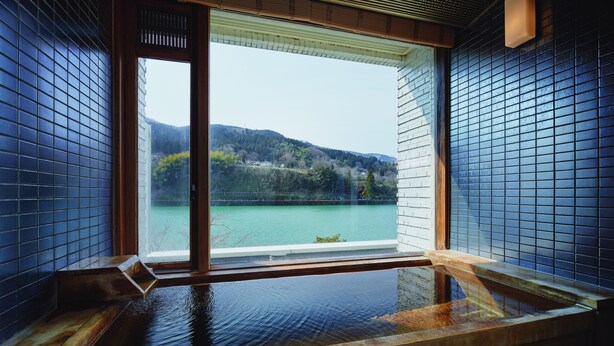 A hot spring bath with a view of a lake and hills. - River Retreat GARAKU (Toyama)