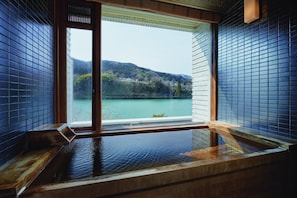 A hot spring bath with a view of a lake and hills. - River Retreat GARAKU (Toyama)