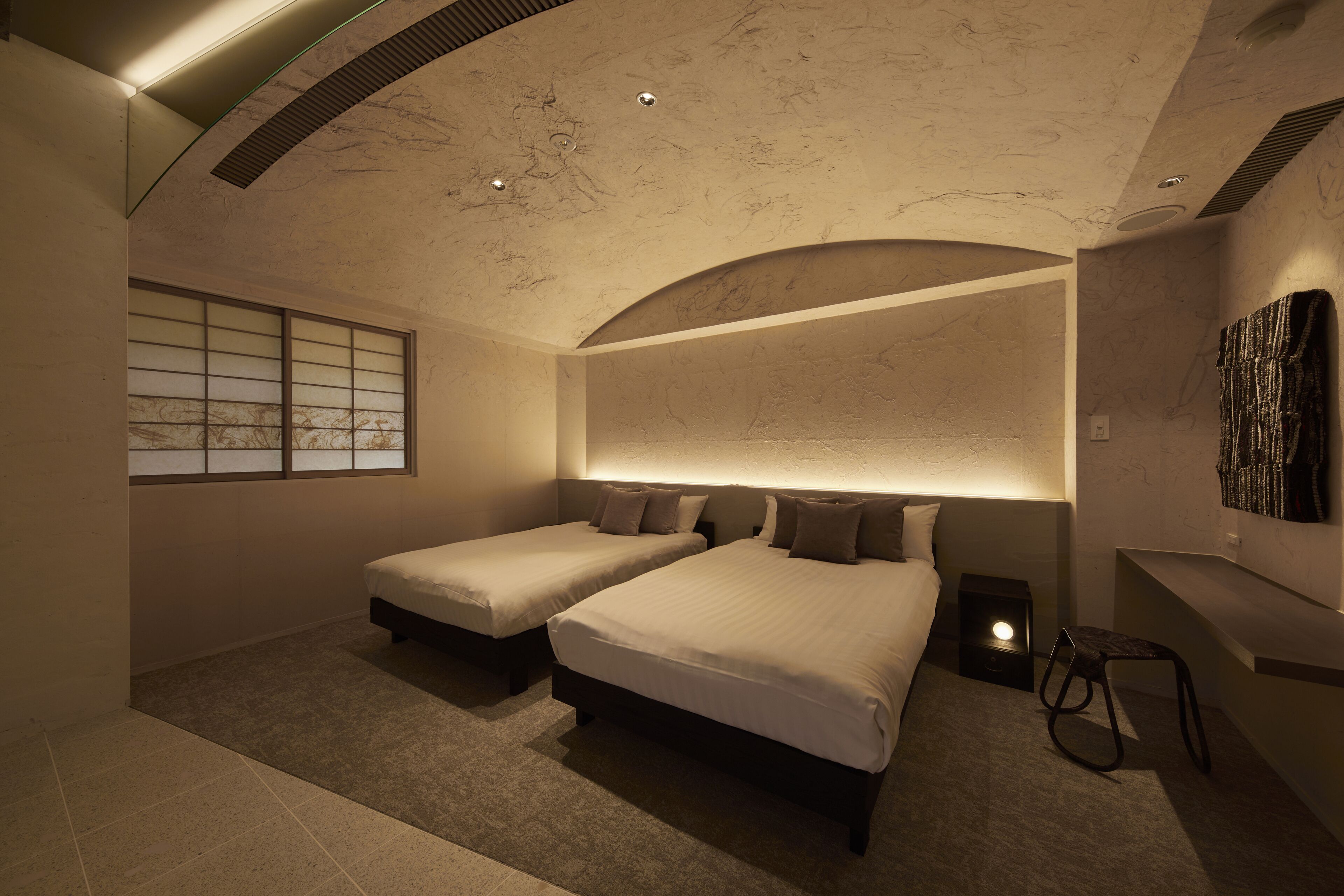 A modern bedroom with two beds, a window with a view, and a unique ceiling design.