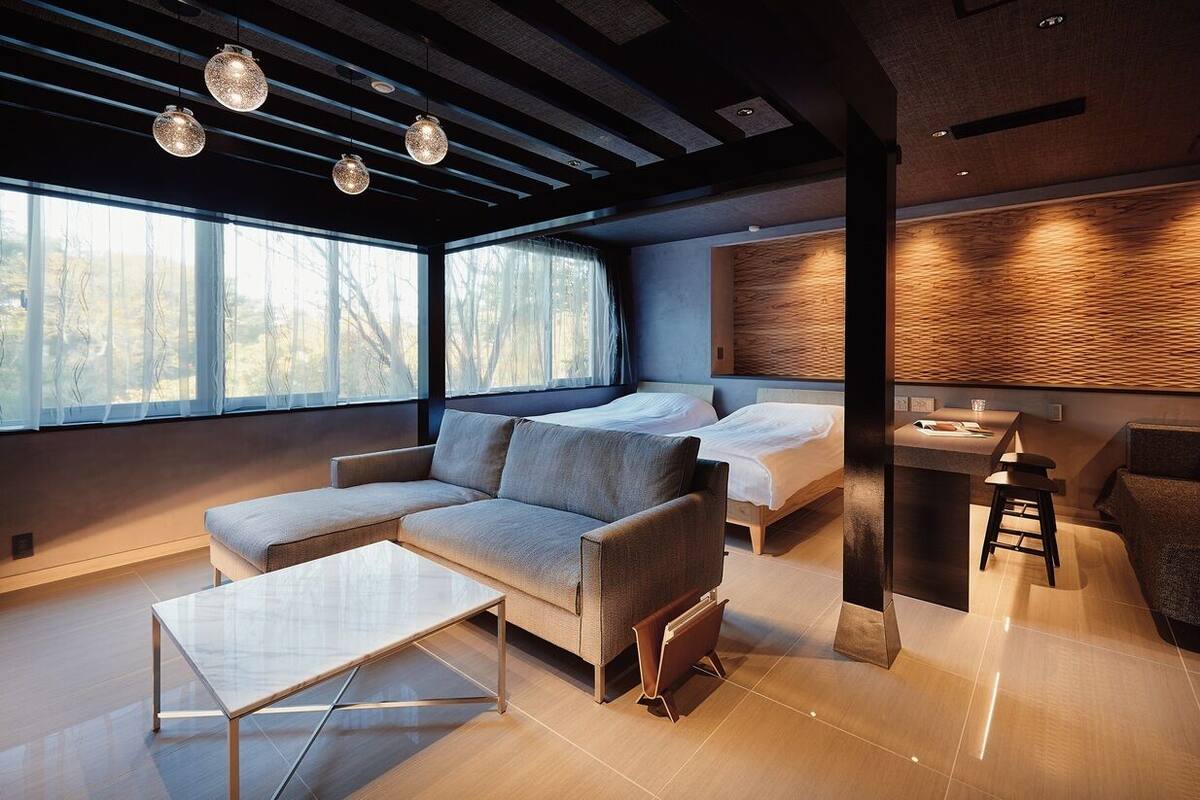 A modern living room with a sofa, a coffee table, and a dining area with a small table and stools.
