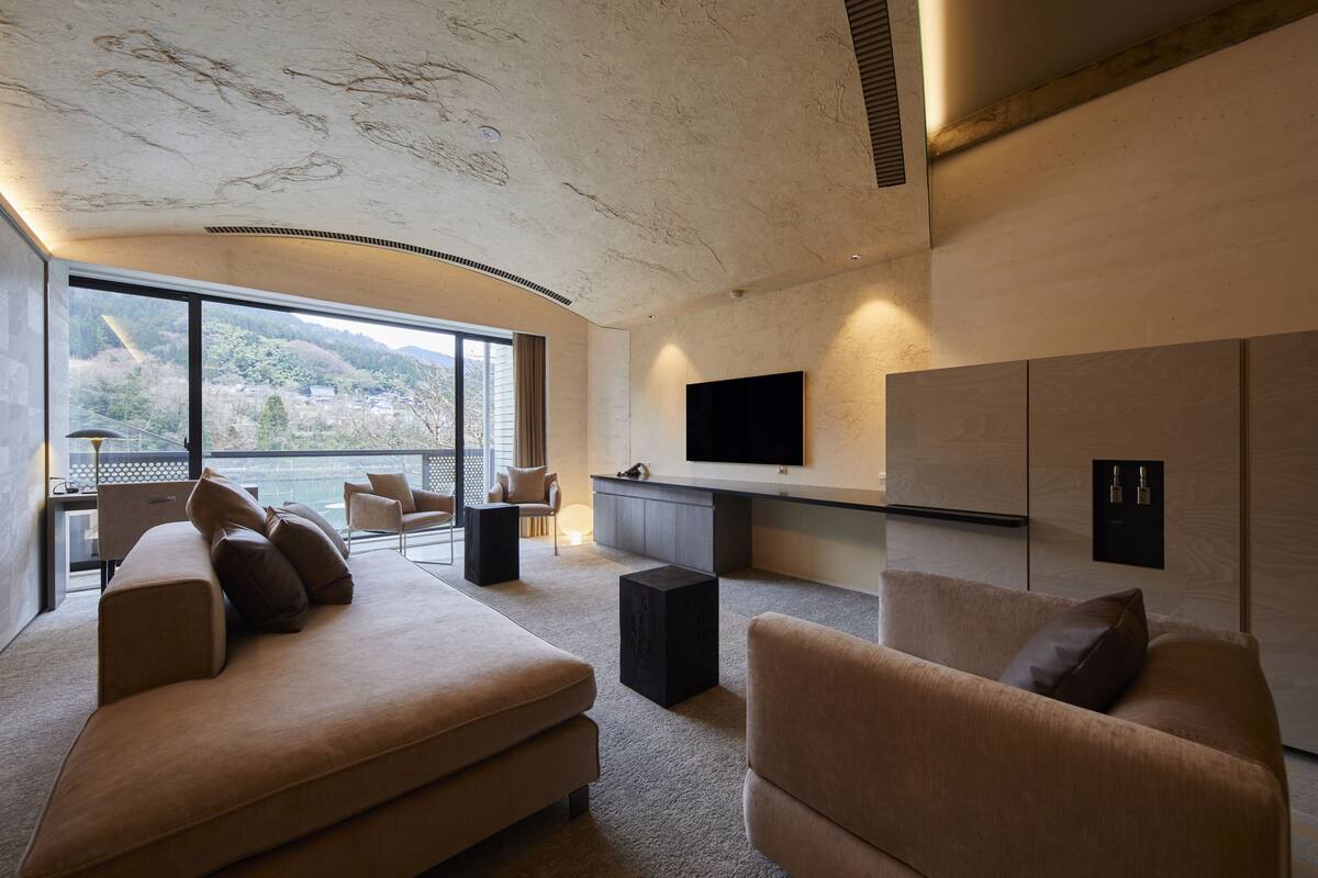 A modern living room with a large window, a flat-screen TV, and a minimalist design.