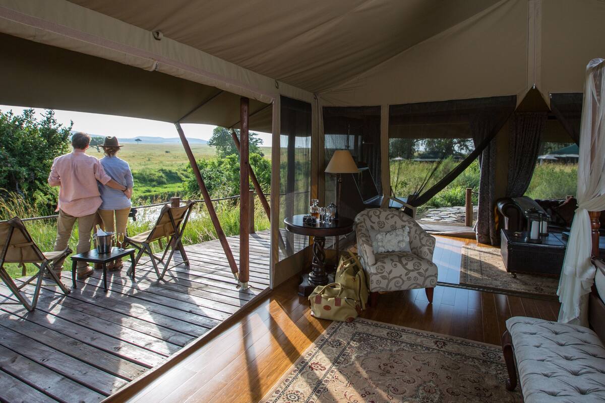Un espace extérieur abrité doté d’une terrasse en bois, d’un coin salon confortable et d’une vue sur la campagne.