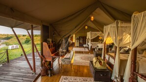 Eine Zelteinrichtung mit Holzterrasse, Essbereich und einem Himmelsbett.