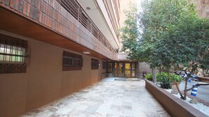 A courtyard with a tiled floor, a brick wall, and a tree.