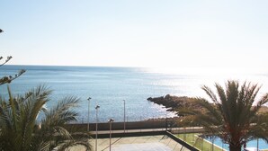 A coastal view with a clear sky, a rocky shoreline, and a pool area.