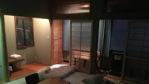 Un espace de vie compact comprenant un canapé, une petite table et une fenêtre dotée de portes coulissantes traditionnelles.
