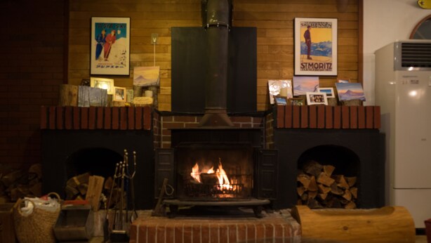 Un salon chaleureux avec une cheminée en briques, une cheminée en bois et un climatiseur moderne.