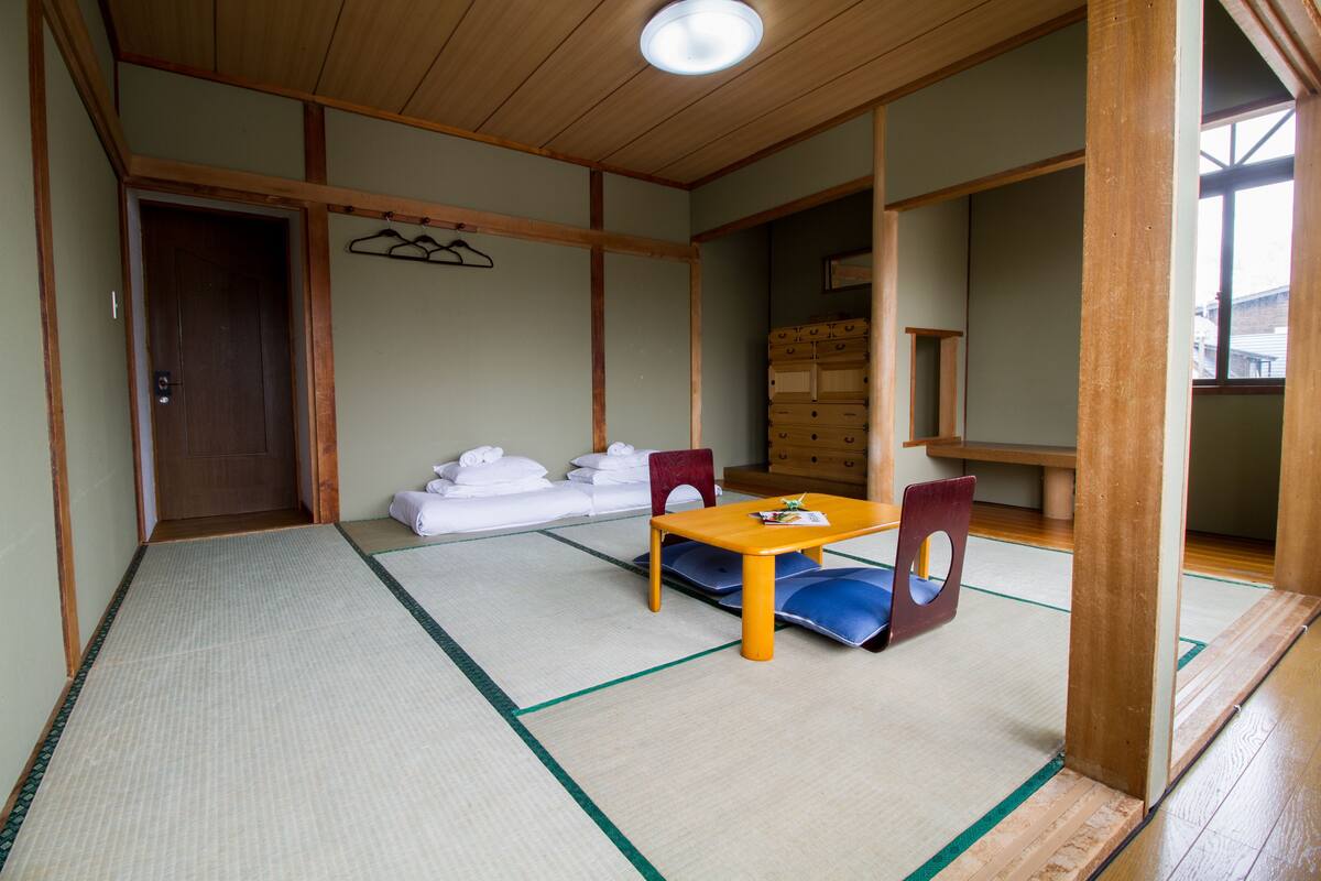 Une pièce de style japonais traditionnel, avec un sol recouvert de tatamis, une petite table en bois et un futon servant de lit.