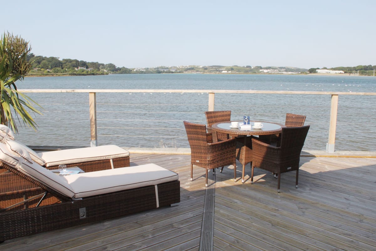 A deck with wicker furniture and a view of the water.