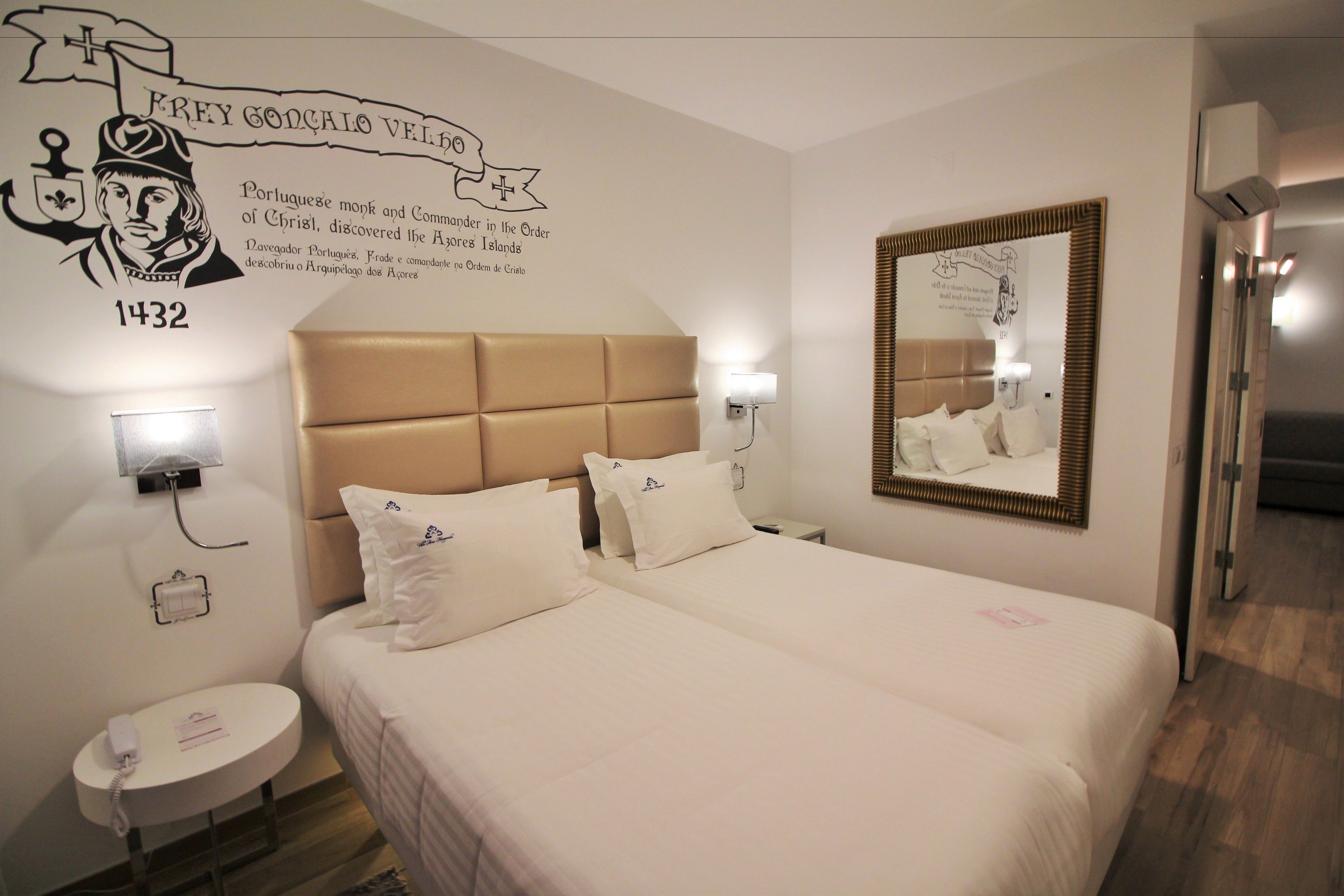 Een hotelkamer met een groot bed, twee nachtkastjes, een spiegel aan de muur en een decoratie.