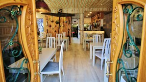 Een restaurant interieur met houten details, witte stoelen en een bar.