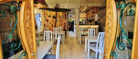 Interior de restaurante con decoración de madera, sillas blancas y una zona de bar.