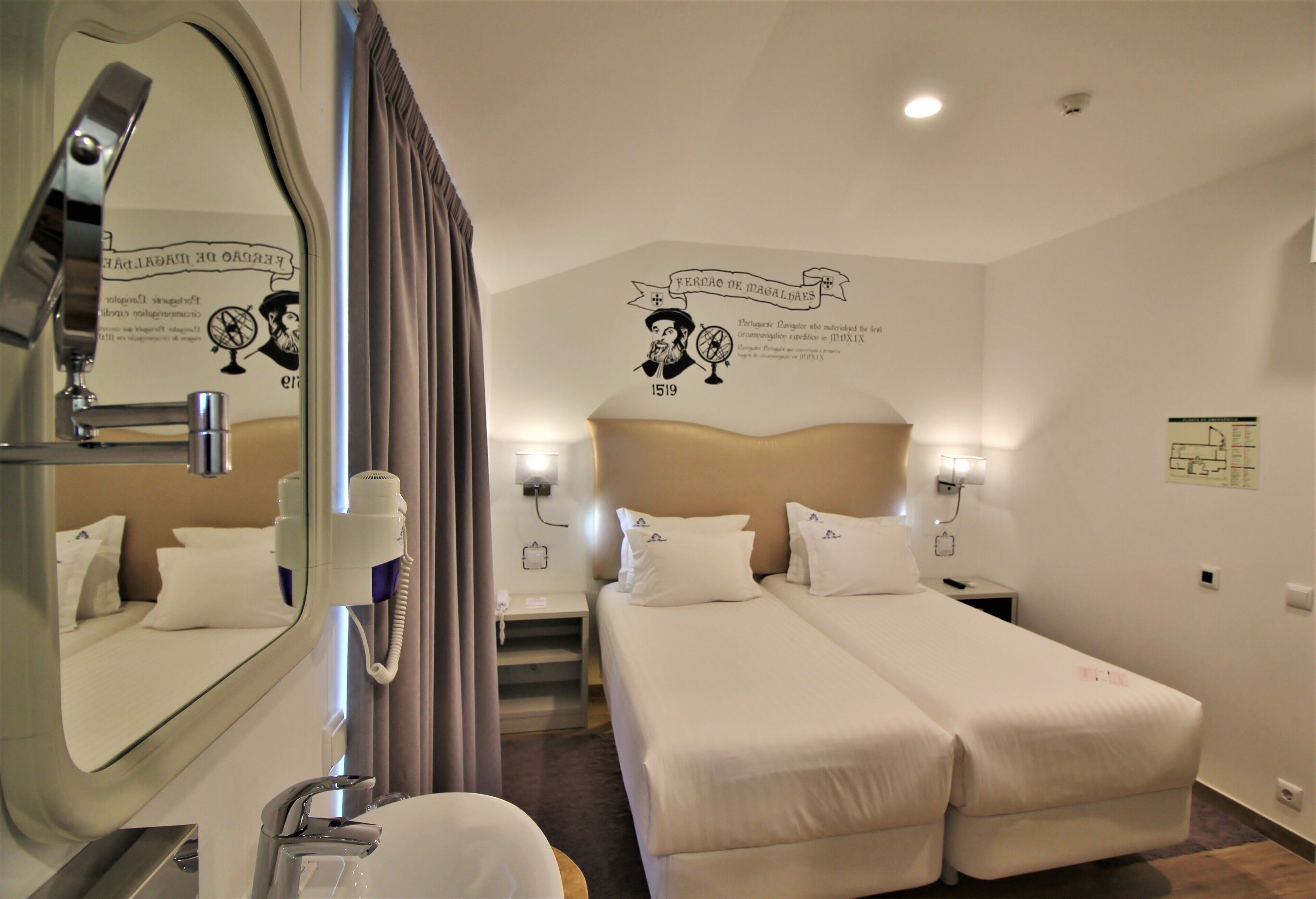 Une chambre d’hôtel avec deux lits, une salle de bain et un miroir.