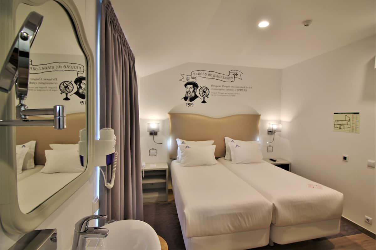 Une chambre d’hôtel avec deux lits, une salle de bain et un miroir.