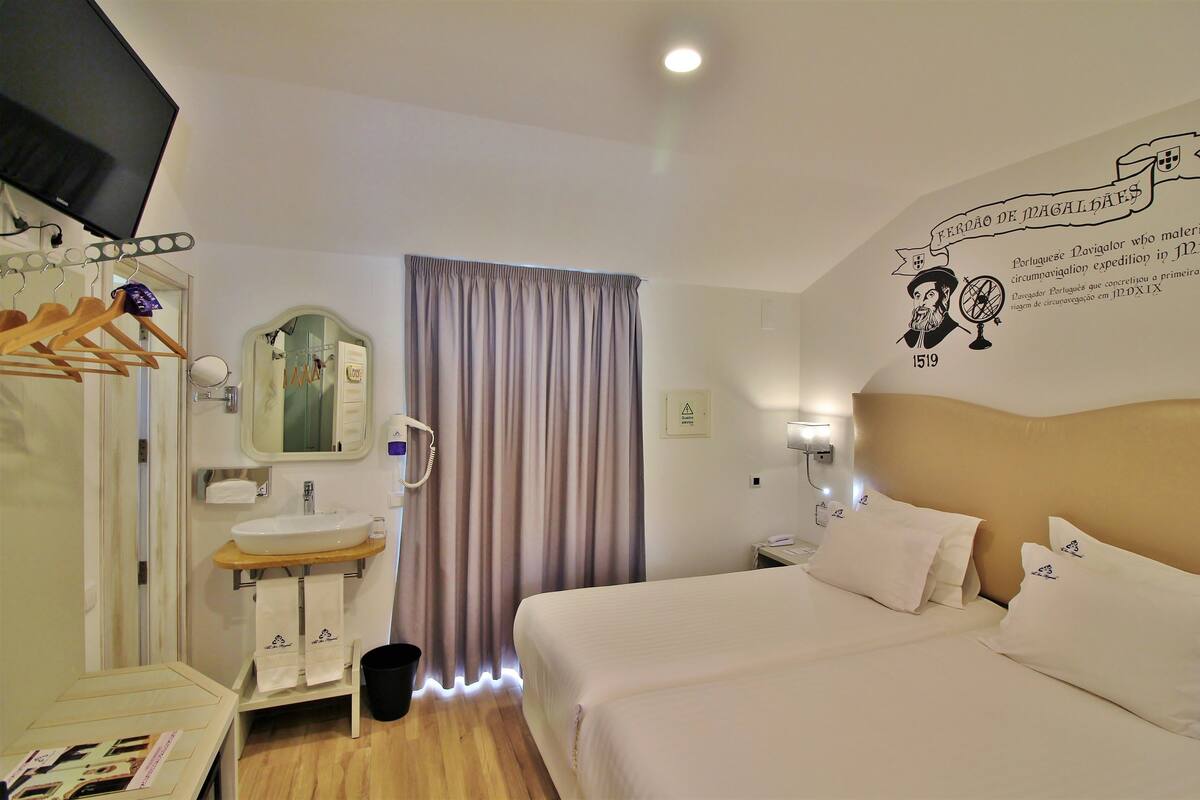 Une chambre d’hôtel équipée d’un lit, d’une table de chevet, d’un miroir et d’un élément décoratif mural.
