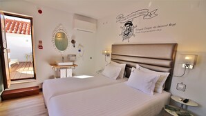 Hotelkamer met een groot bed, een nachtkastje, een klein nachtkastje, een spiegel, een wandairconditioner en een raam met uitzicht.