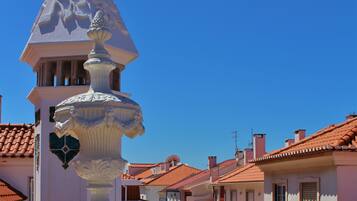 Una calle con tejados de terracota y un edificio blanco con una fuente decorativa.