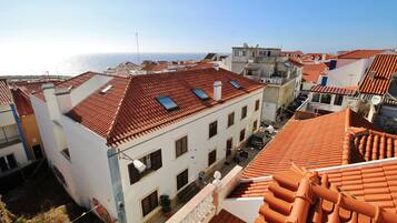 A residential area with terracotta-tiled roofs, a clear view of the sea, and a mix of building styles.