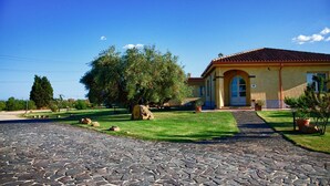 A house with a paved driveway, a lawn, and a large tree. - Hotel Tanca Irde (Capoterra)