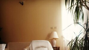 A cozy living room with a sofa, a glass coffee table with pastries, a lamp, and a potted plant. - Hotel Tanca Irde (Capoterra)