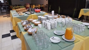 Een buffetopstelling met verschillende soorten eten, borden en glazen.