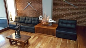 Een woonkamer met een zwarte leren bank, een houten salontafel en een decoratief model schip.