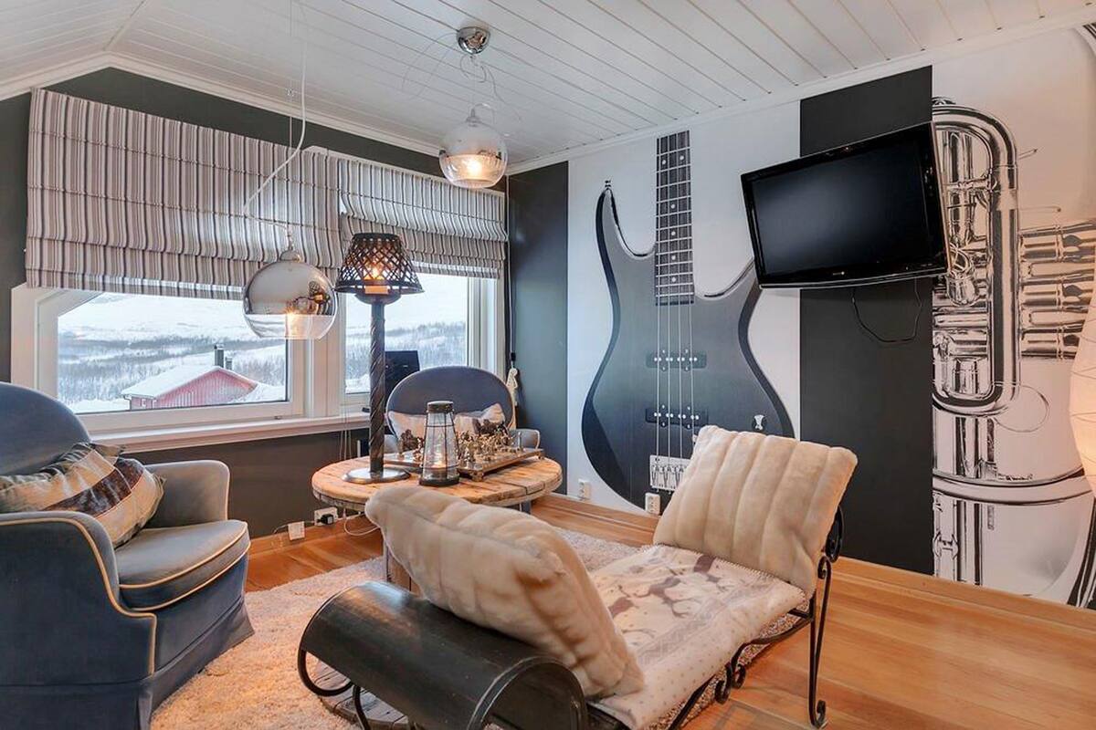 A living room with a large window, a guitar wall art, a TV, and a fireplace.