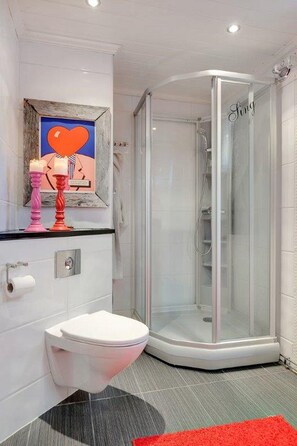 A modern bathroom with a glass shower enclosure, a white toilet, and a red rug. - RIBO Apartment Katterjokk (Riksgränsen)