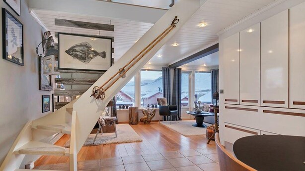 A modern interior with a staircase, wooden flooring, a dining area, and a view of the outside. - RIBO Apartment Katterjokk (Riksgränsen)
