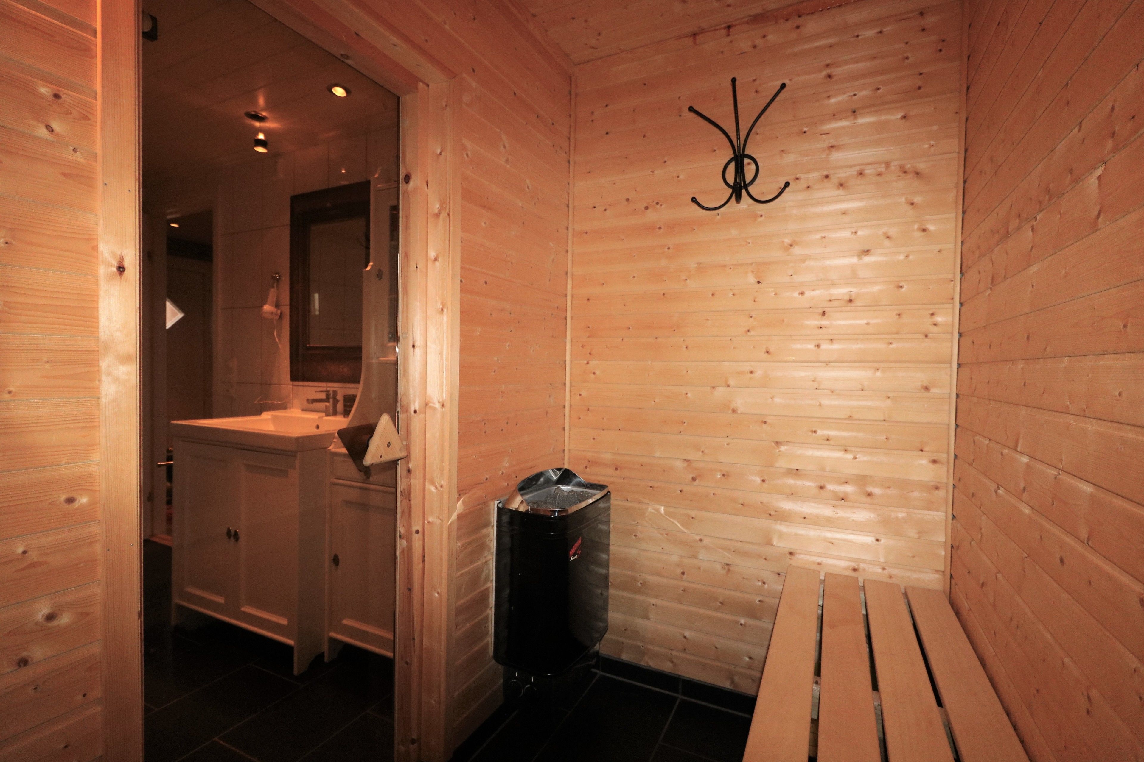 Een houten interieur met een bank, een wastafel en een afvalbak.