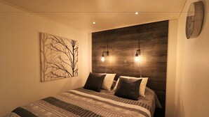 A bedroom with a bed, a wall-mounted clock, and a wooden accent wall. - RIBO Apartment Katterjokk (Riksgränsen)