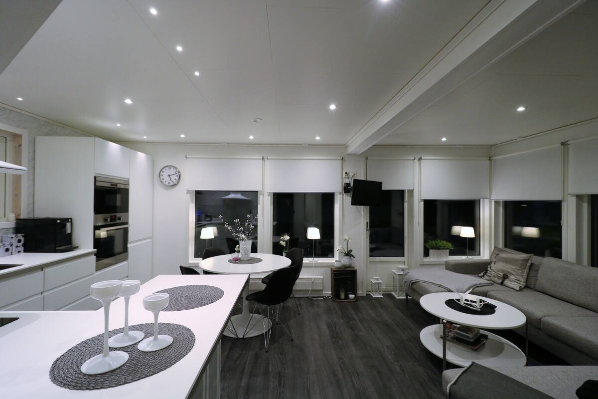 A modern living room with a dining area, a sofa, and a TV.