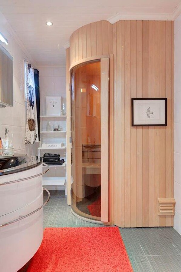 A modern bathroom with a curved vanity, a red rug, and a wooden panel wall.