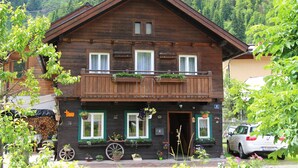 Eine Holzchalet mit Balkon, Eingangstür und kleinem Garten mit Blumentöpfen.