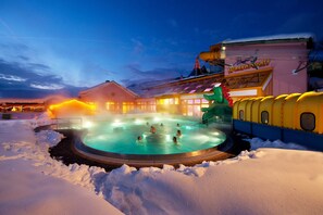A heated outdoor swimming pool surrounded by snow, with a building labeled "Wasservelt" in the background. - Ferienhaus Peterlhaus (Kleinarl)