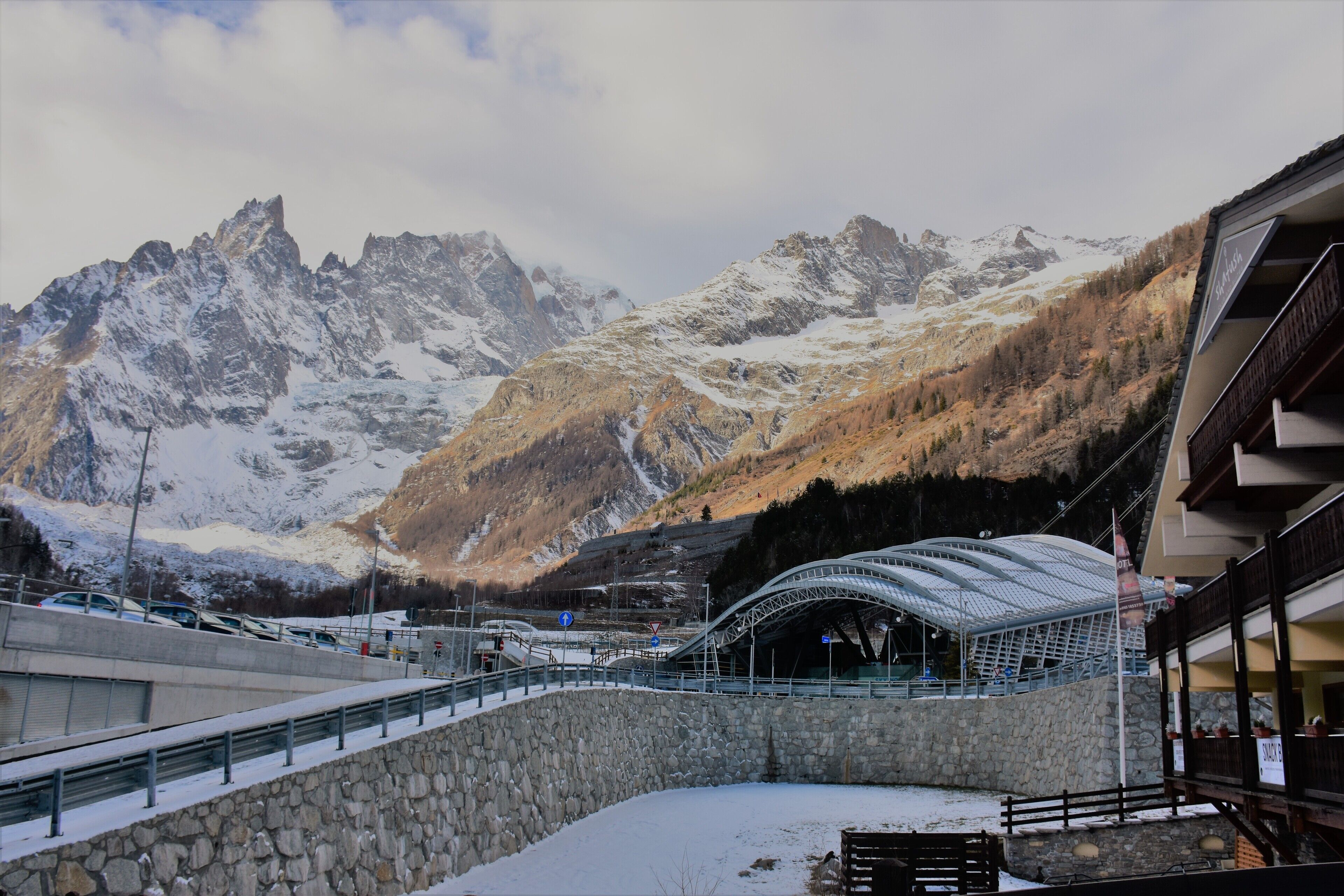 A snow-covered mountain landscape with a modern building featuring a curved glass roof.