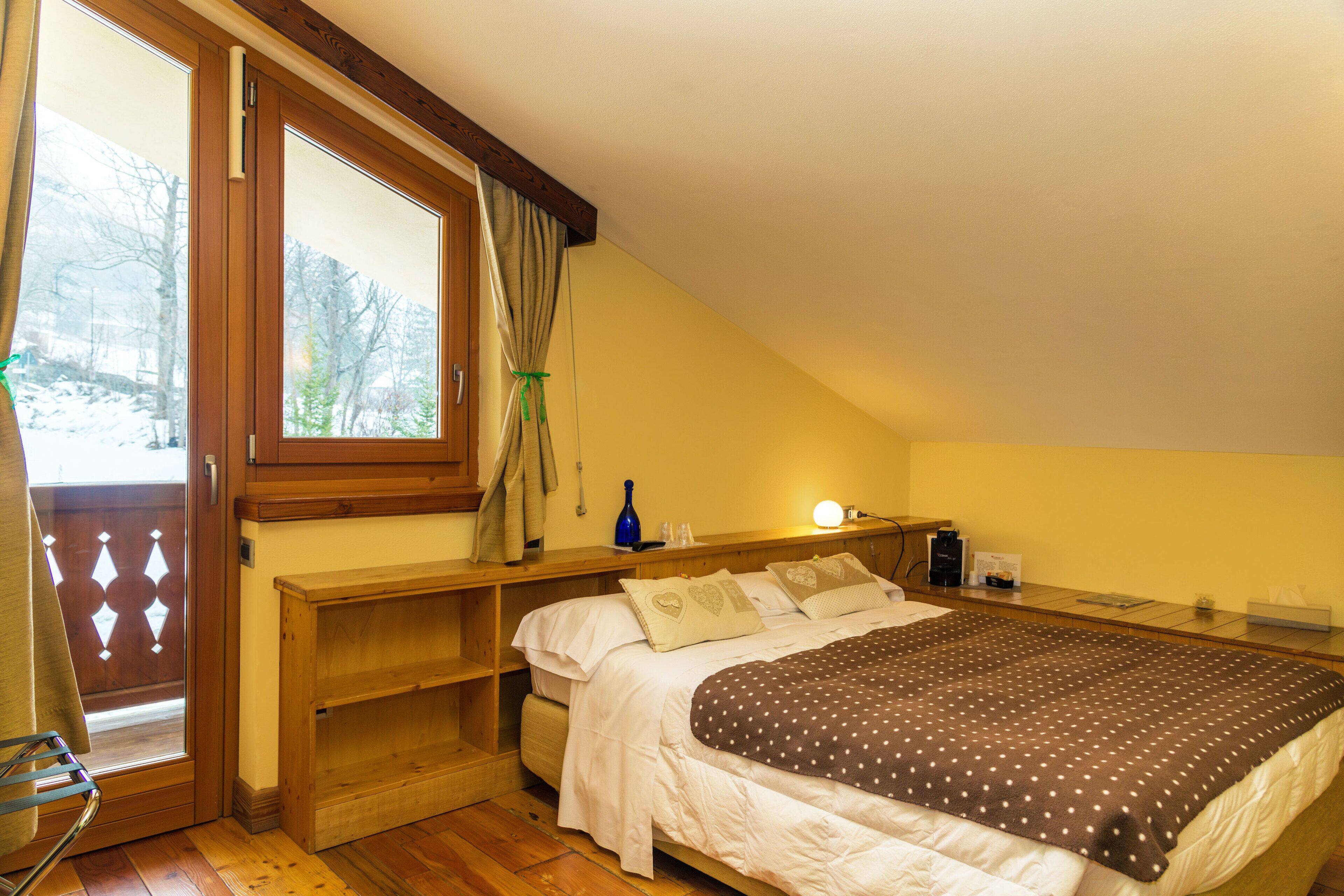 Ein Schlafzimmer mit einem Bett, einem Nachttisch, einer Lampe und einem Fenster mit Vorhängen.