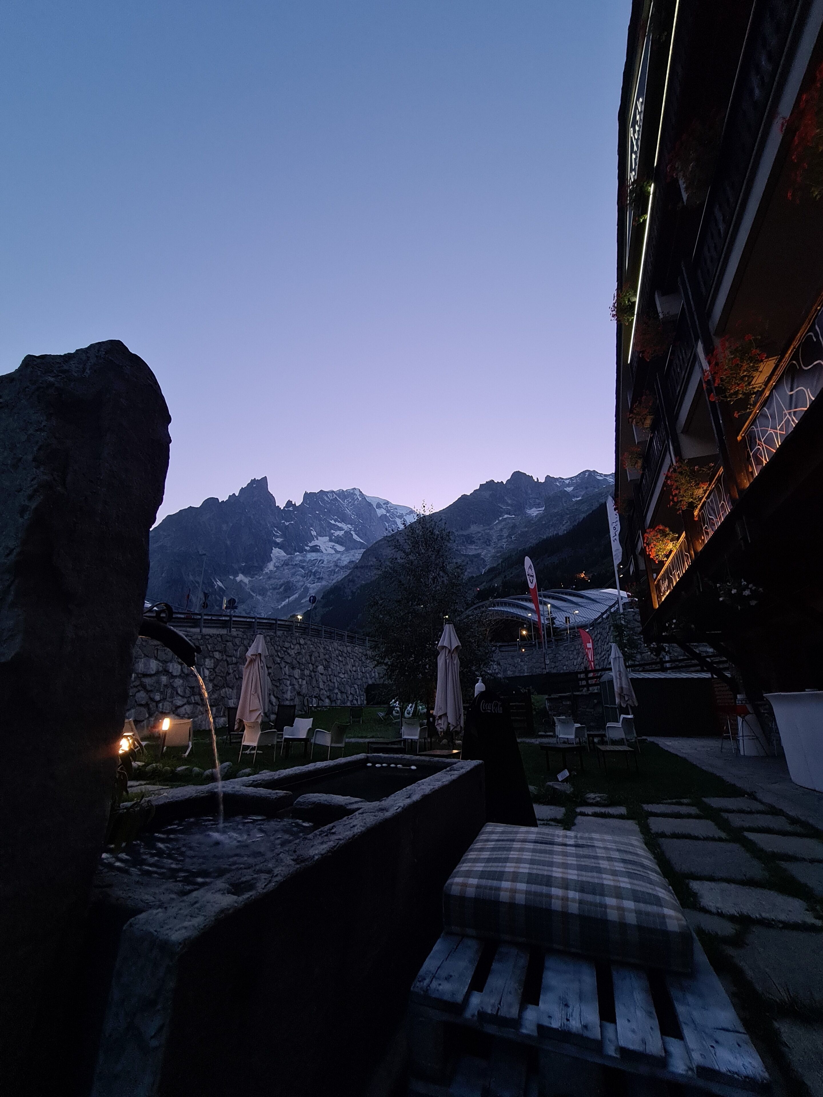 A terrace with stone walls, a water feature, and a view of snow-capped mountains.