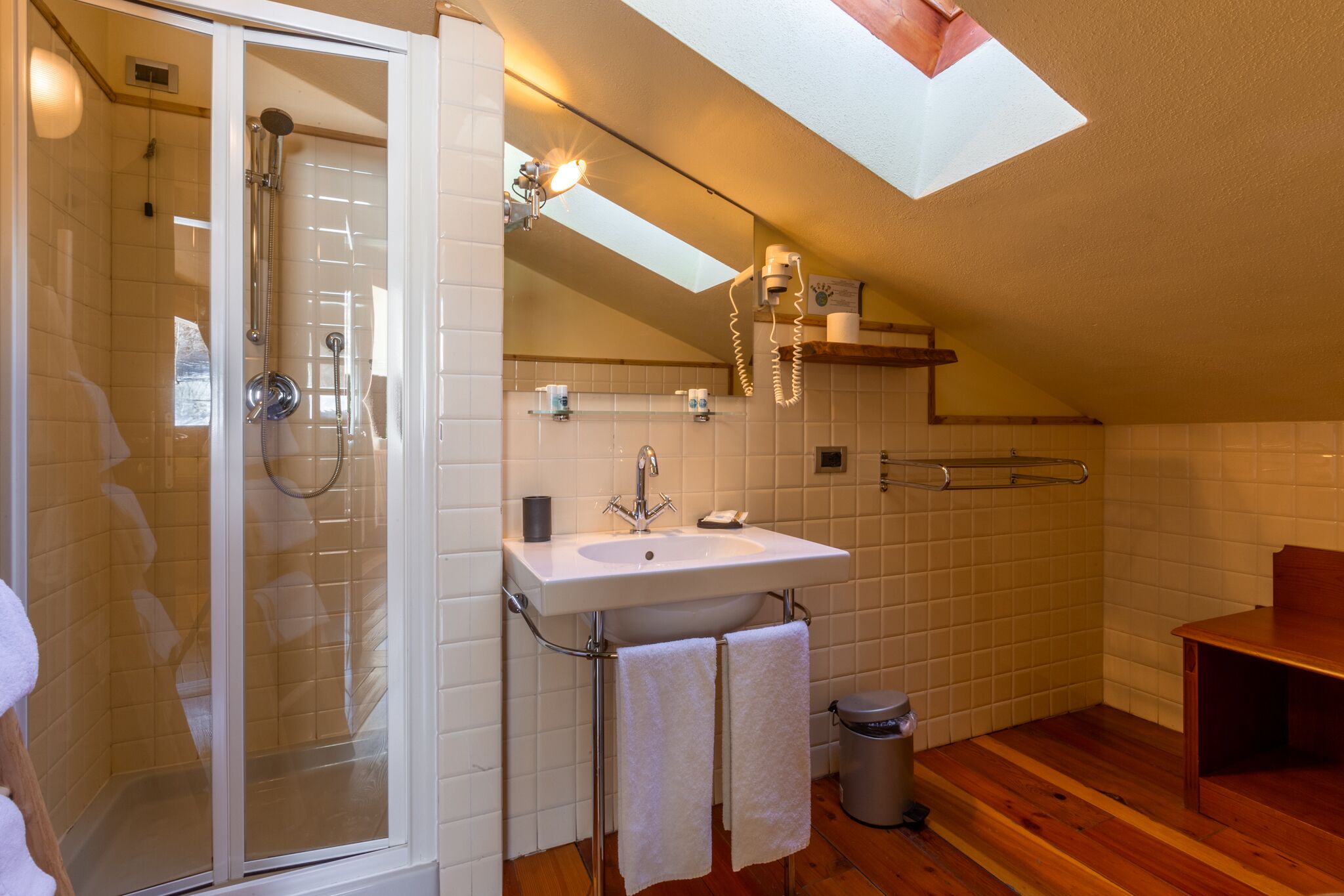 Une salle de bain moderne avec une douche à parois de verre, un lavabo blanc et un meuble-lavabo en bois.