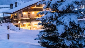 A snow-covered lodge with a balcony and a mountain backdrop. - Shatush Hotel (Courmayeur)