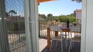 A balcony with a table and chairs, a bottle of wine, and a view of the surrounding area. - Gorgonia Suites (Sali)