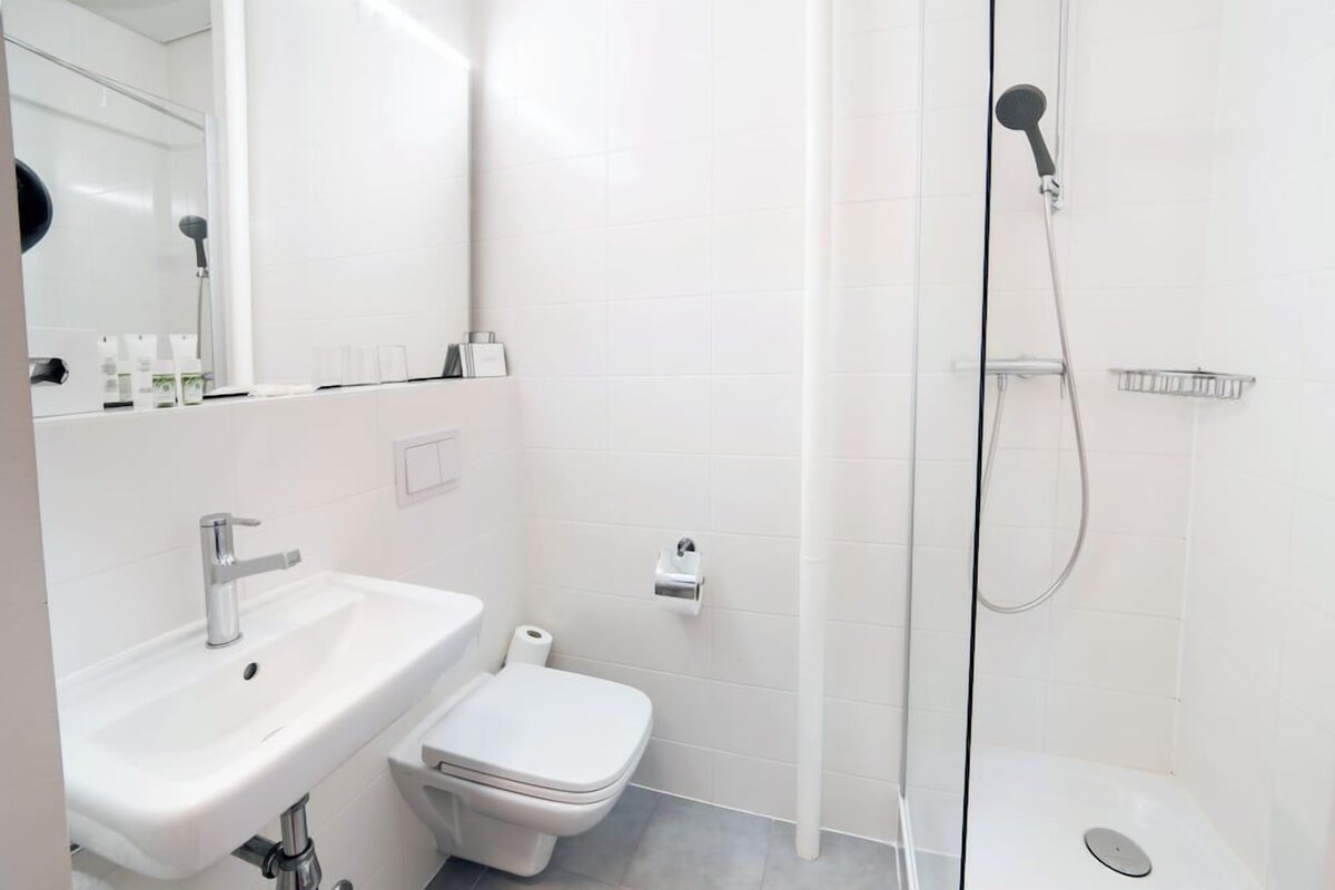 A modern bathroom with a sink, toilet, and glass-enclosed shower.