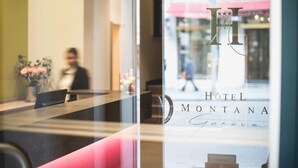 A hotel reception desk with a glass partition. The hotel's name, HOTEL MONTANA, is visible on the glass. - Hotel Montana (Geneva)